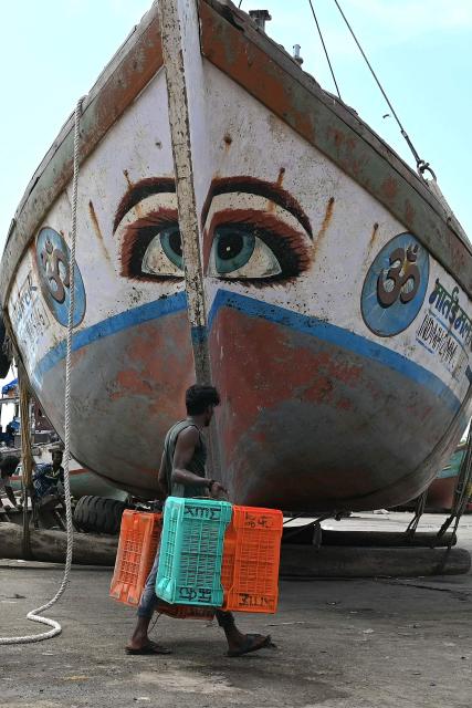 A fishermen carries empty baskets past a boat at Madh Island in Mumbai on June 3, 2026 following the annual 61-day fishing ban along India's coastal region to protect marine life during the monsoon breeding season. (Photo by Indranil Mukherjee / AFP)