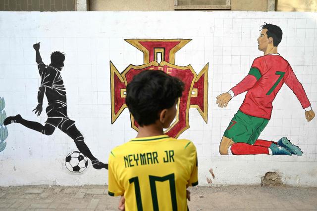 A young boy wearing a Brazil's forward Neymar jersey looks at murals along a street in Karachi on June 3, 2026 ahead the FIFA 2026 World Cup football tournament. (Photo by Rizwan TABASSUM / AFP)