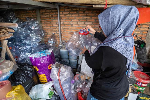 A waste bank employee sorts household inorganic waste, in the form of cardboard and plastic bottles, in Jakarta on June 4, 2026, as part of instructions issued by Jakarta's Provincial Government that requires residents to separate and sort waste to reduce the capital's mounting waste burden. (Photo by BAY ISMOYO / AFP)