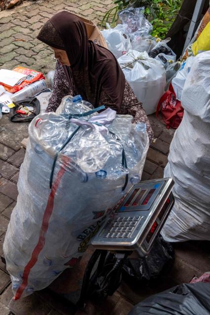 A waste bank employee weighs household inorganic waste, in the form of cardboard and plastic bottles, in Jakarta on June 4, 2026, as part of instructions issued by Jakarta's Provincial Government that requires residents to separate and sort waste to reduce the capital's mounting waste burden. (Photo by BAY ISMOYO / AFP)