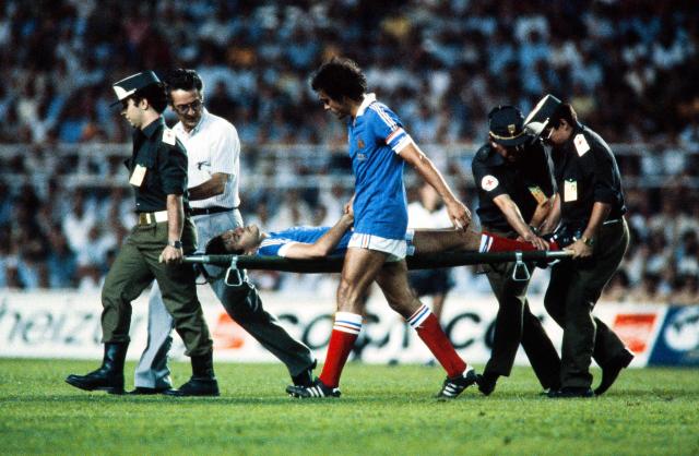 (FILES) French midfielder Michel Platini (C) holds the hand of French defender Patrick Battiston injured during the 1982 World Cup semifinal football match between West Germany and France on July 8, 1982 in Seville. From the artistry of Pele to Maradona's "Hand of God", Zidane's headbutt and the clash between France's Battiston against Germany's Schumacher... Heroic, historic, dramatic, bizarre, spectacular, jubilantthe glorious history of the World Cup is full of unforgettable moments. (Photo by AFP)