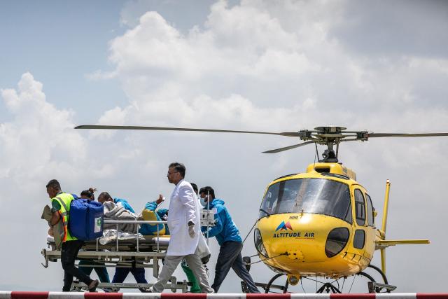 TOPSHOT - Medics and rescuers transfer mountaineer Dawa Sherpa from a helicopter upon his arrival at the HAMS Hospital in Kathmandu on June 4, 2026. A Nepali climbing guide who went missing on Mount Everest for six days and was believed dead has been found alive after crawling alone almost to Base Camp, officials told AFP on June 4. (Photo by PRABIN RANABHAT / AFP)