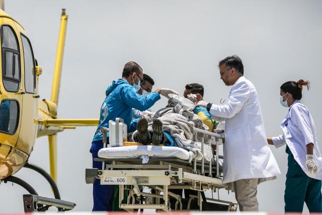 Medics and rescuers transfer mountaineer Dawa Sherpa from a helicopter upon his arrival at the HAMS Hospital in Kathmandu on June 4, 2026. A Nepali climbing guide who went missing on Mount Everest for six days and was believed dead has been found alive after crawling alone almost to Base Camp, officials told AFP on June 4. (Photo by PRABIN RANABHAT / AFP)