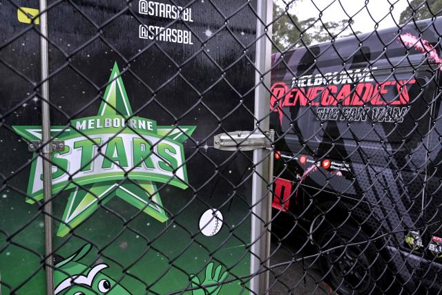 Two vans from the Melbourne Stars and Melbourne Renegades cricket Big Bash League (BBL) teams sit in a compound in Melbourne on June 4, 2026. Melbourne's two Big Bash League sides -- the Stars and the Renegades -- are set to merge into a single Twenty20 franchise, but the move has sparked "confusion, uncertainty and anxiety" among players. Cricket Victoria's plan unveiled on June 3, will see the Melbourne Stars retained by the state governing body but rebranded and the Melbourne Renegades sold entirely to private investors. (Photo by William WEST / AFP)