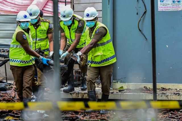 EDITORS NOTE: Graphic content / Sri Lanka's Scene of Crime Officers (SOCO) carry the charred remains of a resident in Batagoda on June 4, 2026 a day after a fire broke out at an elder care home. The manager of a Sri Lankan care home was arrested June 4, a day after a fire killed 12 residents and injured six others, officials said. (Photo by Ishara S. KODIKARA / AFP)
