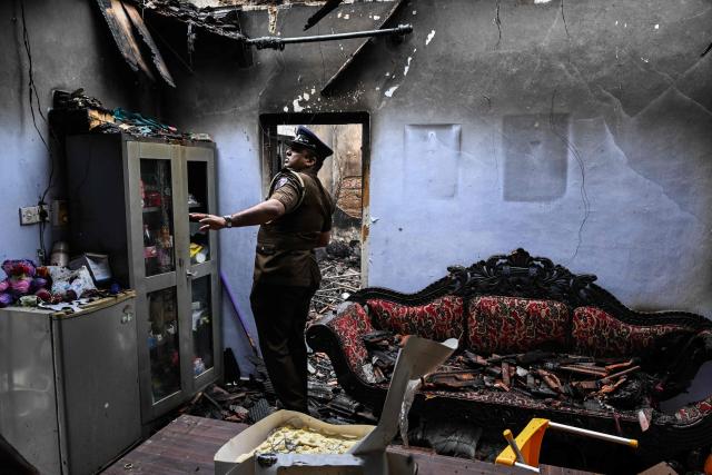 A police personnel inspects the burnt house a day after a fire broke out at an elder care home in Sri Lanka's Batagoda on June 4, 2026. The manager of a Sri Lankan care home was arrested June 4, a day after a fire killed 12 residents and injured six others, officials said. (Photo by Ishara S. KODIKARA / AFP)
