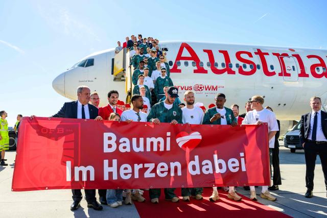 Members of Austria's national football team hold a banner reading "Baumi - with us in our hearts", addressing injured team player Christoph Baumgartner nicknamed "Baumi" who will miss the World Cup due to injury, as the team boards a plane before departing from the Schwechat airport near Vienna, Austria, on June 4, 2026, ahead of the FIFA 2026 World Cup. (Photo by MAX SLOVENCIK / APA / AFP) / Austria OUT
