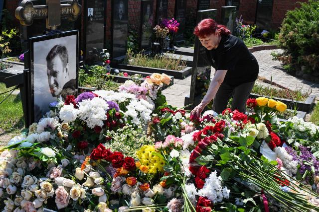 A woman lays flowers at the grave of the late Russian opposition leader Alexei Navalny to mark his 50th birthday at the Borisovo cemetery in Moscow on June 4, 2026. (Photo by Igor IVANKO / AFP) / NAVALNY HAS BEEN DECLARED "EXTREMIST" BY RUSSIAN AUTHORITIES. IN RUSSIA, ANYBODY WHO MENTIONS NAVALNY OR HIS ANTI-CORRUPTION FOUNDATION WITHOUT STATING THAT THEY HAVE BEEN DECLARED "EXTREMIST" IS SUBJECT TO FINES OR UP TO FOUR YEARS IN PRISON FOR REPEATED OFFENCES.
