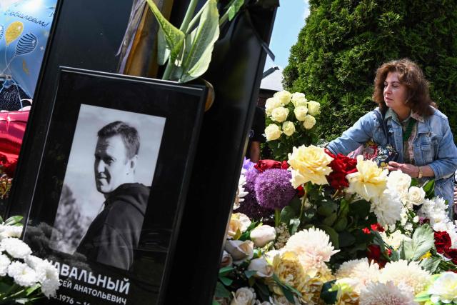 A woman lays flowers at the grave of the late Russian opposition leader Alexei Navalny to mark his 50th birthday at the Borisovo cemetery in Moscow on June 4, 2026. (Photo by Igor IVANKO / AFP) / NAVALNY HAS BEEN DECLARED "EXTREMIST" BY RUSSIAN AUTHORITIES. IN RUSSIA, ANYBODY WHO MENTIONS NAVALNY OR HIS ANTI-CORRUPTION FOUNDATION WITHOUT STATING THAT THEY HAVE BEEN DECLARED "EXTREMIST" IS SUBJECT TO FINES OR UP TO FOUR YEARS IN PRISON FOR REPEATED OFFENCES.