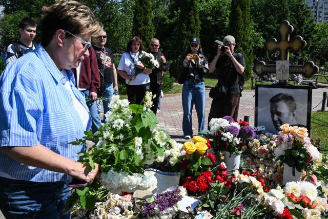 A woman lays flowers at the grave of the late Russian opposition leader Alexei Navalny to mark his 50th birthday at the Borisovo cemetery in Moscow on June 4, 2026. (Photo by Igor IVANKO / AFP) / NAVALNY HAS BEEN DECLARED "EXTREMIST" BY RUSSIAN AUTHORITIES. IN RUSSIA, ANYBODY WHO MENTIONS NAVALNY OR HIS ANTI-CORRUPTION FOUNDATION WITHOUT STATING THAT THEY HAVE BEEN DECLARED "EXTREMIST" IS SUBJECT TO FINES OR UP TO FOUR YEARS IN PRISON FOR REPEATED OFFENCES.