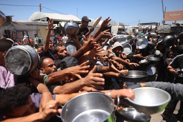 Displaced Palestinians, including women and children, gather to receive hot meals distributed by a charity kitchen in the Khan Yunis refugee camp in the southern Gaza Strip, on June 4, 2026. The food distribution comes amid ongoing shortages of food supplies caused by Israeli attacks and restrictions on aid entering the Gaza Strip. (Photo by Bashar Taleb / AFP)