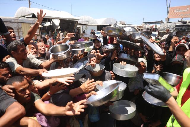 Displaced Palestinians, including women and children, gather to receive hot meals distributed by a charity kitchen in the Khan Yunis refugee camp in the southern Gaza Strip, on June 4, 2026. The food distribution comes amid ongoing shortages of food supplies caused by Israeli attacks and restrictions on aid entering the Gaza Strip. (Photo by Bashar Taleb / AFP)