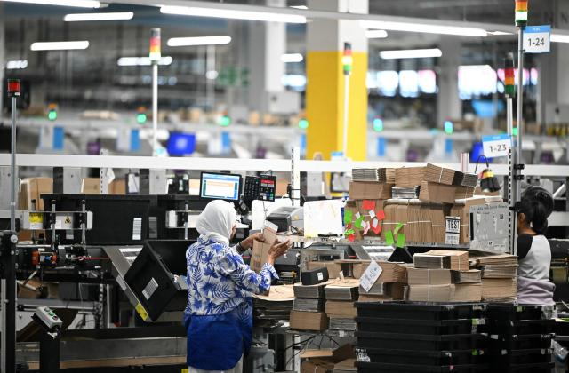 Employees work on the packing line inside Amazon's LCY3 Fulfillment Centre in Dartford, east of London, on June 4, 2026, on the second day of company's 'Delivering the Future EMEA ‘26' event. (Photo by JUSTIN TALLIS / AFP)
