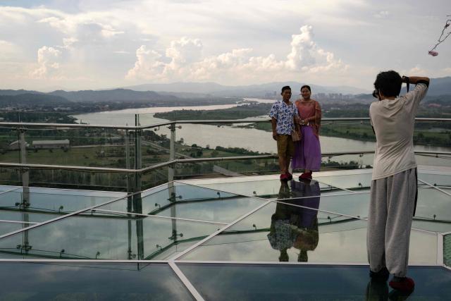 People stand atop a skywalk overlooking the Mekong River and the Golden Triangle Special Economic Zone within Laos’ Bokeo province (R) from the Golden Triangle in Thailand's Chiang Rai province on June 4, 2026. (Photo by Lillian SUWANRUMPHA / AFP)