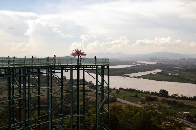 People stand atop a skywalk overlooking the Mekong River and the Golden Triangle Special Economic Zone within Laos’ Bokeo province (R) from the Golden Triangle in Thailand's Chiang Rai province on June 4, 2026. (Photo by Lillian SUWANRUMPHA / AFP)