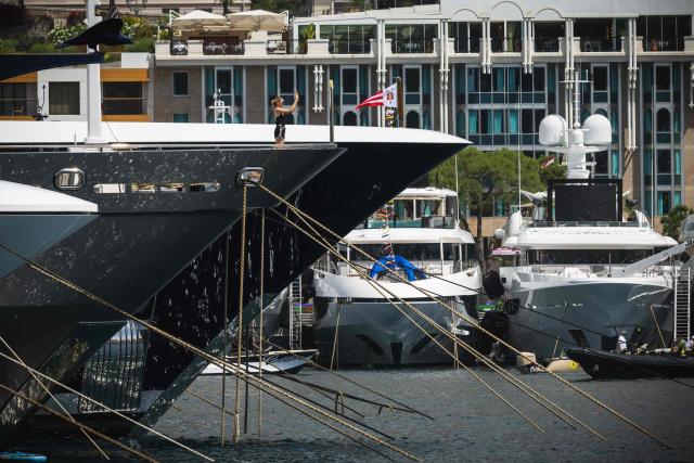 A woman uses her phone aboard a yacht in Monaco’s harbour overlooking the Circuit de Monaco on June 4, 2026, ahead of the Formula One Monaco Grand Prix. (Photo by Andrej ISAKOVIC / AFP)