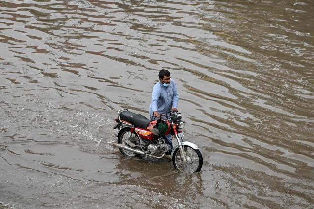 A motorcyclist wades through a flooded road after a spell of heavy rain in Islamabad on June 4, 2026. (Photo by Farooq NAEEM / AFP)