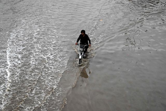 A motorcyclist rides through a flooded road after a spell of heavy rain in Islamabad on June 4, 2026. (Photo by Farooq NAEEM / AFP)