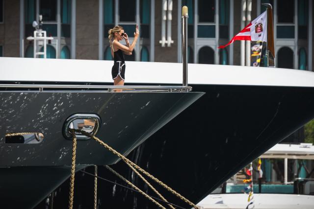 A woman uses her phone aboard a yacht in Monaco’s harbour overlooking the Circuit de Monaco on June 4, 2026, ahead of the Formula One Monaco Grand Prix. (Photo by Andrej ISAKOVIC / AFP)