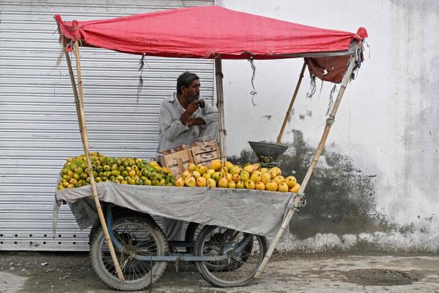 A mango vendor drinks tea at his roadside cart in Rawalpindi on June 4, 2026. (Photo by Farooq NAEEM / AFP)