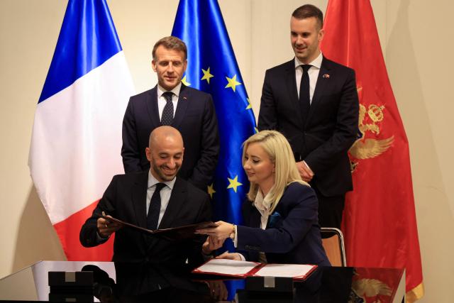 France's President Emmanuel Macron (Top L) and Montenegro's Prime Minister Milojko Spajic watch as France's junior Minister in charge of Europe Benjamin Haddad (Bottom L) and Montenegro's Minister of European Affairs Maida Gorcevic sign a Memorandum of Understanding on the enlargement of the European Union during a signing ceremony covering transport infrastructure, energy and defence cooperation during Macron's first official visit to Montenegro in Cetinje on June 4, 2026. (Photo by Ludovic MARIN / AFP)