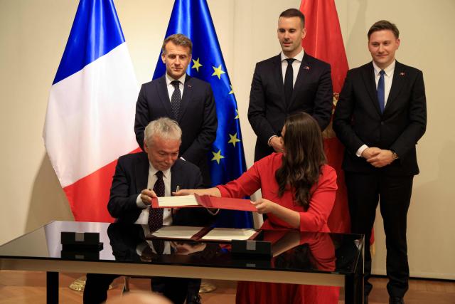France's President Emmanuel Macron (Top-L) and Montenegro's Prime Minister Milojko Spajic (Top-C) watch as Deputy CEO of Bouygues Batiment International Christophe Petit (Bottom L)  and Montenegro's Minister of Public Works Majda Adzovic sign a contract for the construction of a university hospital in Podgorica as part of a signing ceremony covering transport infrastructure, energy and defence cooperation at the Montenegrin Ministry of Culture and Media during Macron's first official visit to Montenegro in Cetinje on June 4, 2026. (Photo by Ludovic MARIN / AFP)