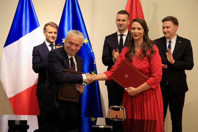 France's President Emmanuel Macron (Top-L) and Montenegro's Prime Minister Milojko Spajic (Top-C) watch as Deputy CEO of Bouygues Batiment International Christophe Petit (2nd L)  and Montenegro's Minister of Public Works Majda Adzovic shake hands after signing a contract for the construction of a university hospital in Podgorica as part of a signing ceremony covering transport infrastructure, energy and defence cooperation at the Montenegrin Ministry of Culture and Media during Macron's first official visit to Montenegro in Cetinje on June 4, 2026. (Photo by Ludovic MARIN / AFP)