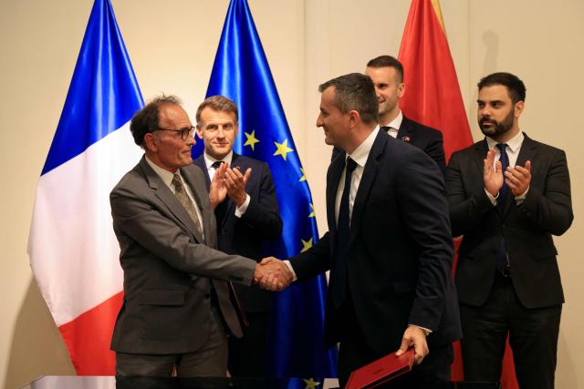 France's President Emmanuel Macron (2nd L) and Montenegro's Prime Minister Milojko Spajic (2nd R) watch as Bouygues' Public Works - Europe Head of Sales & Marketing Benoit Lange (L) and General Director of Monteput Milan Ljiljanic (C) shake hands after signing a Memorandum of Understanding for the construction of a motorway section as part of a signing ceremony covering transport infrastructure, energy and defence cooperation at the Montenegrin Ministry of Culture and Media during Macron's first official visit to Montenegro in Cetinje on June 4, 2026. (Photo by Ludovic MARIN / AFP)