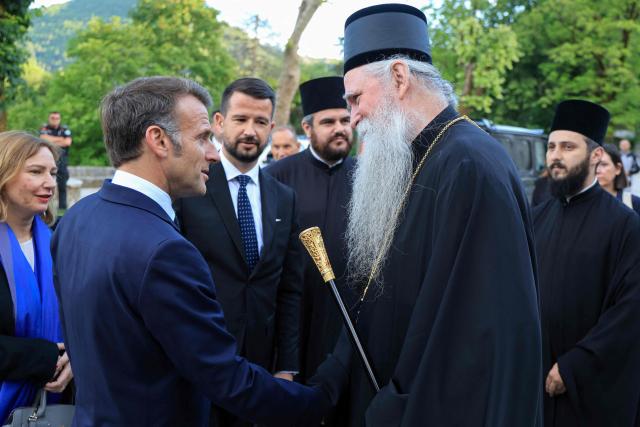 France's President Emmanuel Macron (L) shakes hands with bishop of Montenegro Joanikije Mi?ovi? (R) flanked by Montenegro's President Jakov Milatovic (C) as he arrives for a visit of the Cetinje Monastery during his first official visit to Montenegro ahead of the EU-Western Balkans Summit in Cetinje on June 4, 2026. Founded in 1484, the monastery is one of Montenegro's most significant spiritual and cultural sites and serves as a major center of Serbian Orthodox Christianity in the country. (Photo by Ludovic MARIN / AFP)