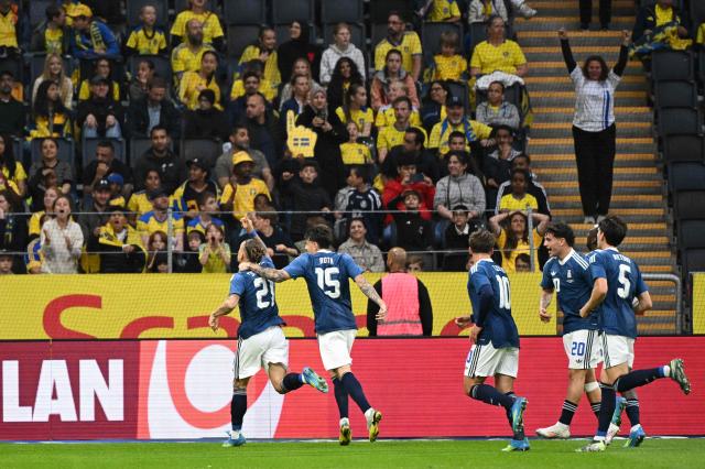 Greece's defender #21 Kostas Tsimikas (L) celebrates scoring his team's first goal with teammates during the friendly match between Sweden and Greece ahead of the 2026 FIFA World Cup football tournament, in Solna, near Stockholm, on June 4, 2026. (Photo by Jonathan Nackstrand / AFP)