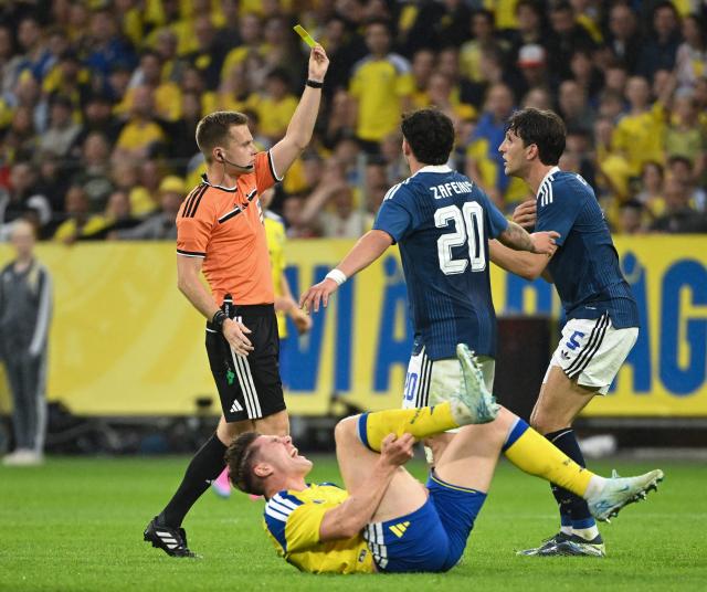 Greece's defender #05 Panagiotis Retsos (R) is shown the yellow card for a foul on Sweden's forward #17 Viktor Gyokeres during the friendly match between Sweden and Greece ahead of the 2026 FIFA World Cup football tournament, in Solna, near Stockholm, on June 4, 2026. (Photo by Jonathan Nackstrand / AFP)