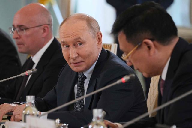 Russian President Vladimir Putin looks at President of Xinhua News Agency Fu Hua while speaking to representatives of international news agencies as General Director of the Russian news agency TASS, Andrey Kondrashov sits nearby during their meeting on the sidelines of the St. Petersburg International Economic Forum at the Constantine Palace in Saint Petersburg on June 4, 2026. (Photo by Dmitry LOVETSKY / POOL / AFP)