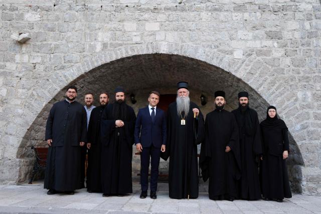 France's President Emmanuel Macron (C) poses for a family photo flanked by bishop of Montenegro Joanikije Micovic and members of the clergy during a visit of the Cetinje Monastery during his first official visit to Montenegro ahead of the EU-Western Balkans Summit in Cetinje on June 4, 2026. Founded in 1484, the monastery is one of Montenegro's most significant spiritual and cultural sites and serves as a major center of Serbian Orthodox Christianity in the country. (Photo by Ludovic MARIN / AFP)