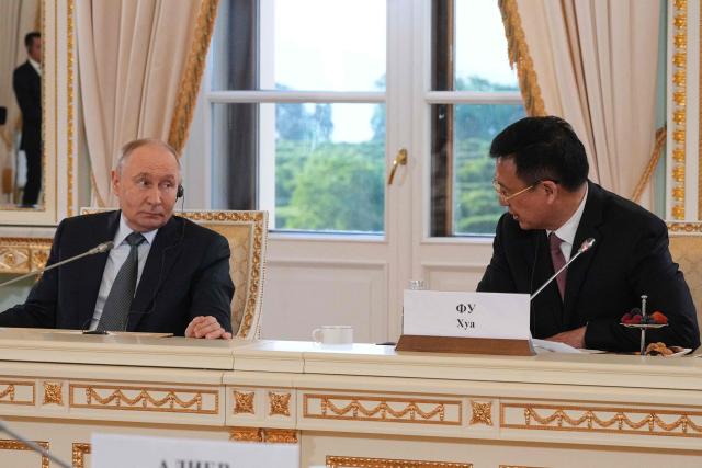 Russian President Vladimir Putin listens to President of Xinhua News Agency Fu Hua during a meeting with representatives of international news agencies on the sidelines of the St. Petersburg International Economic Forum at the Constantine Palace in Saint Petersburg on June 4, 2026. (Photo by Dmitry LOVETSKY / POOL / AFP)