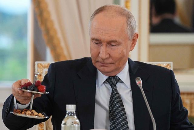 Russian President Vladimir Putin takes a dessert as he arrives to meet with representatives of international news agencies on the sidelines of the St. Petersburg International Economic Forum at the Constantine Palace in Saint Petersburg on June 4, 2026. (Photo by Dmitry LOVETSKY / POOL / AFP)