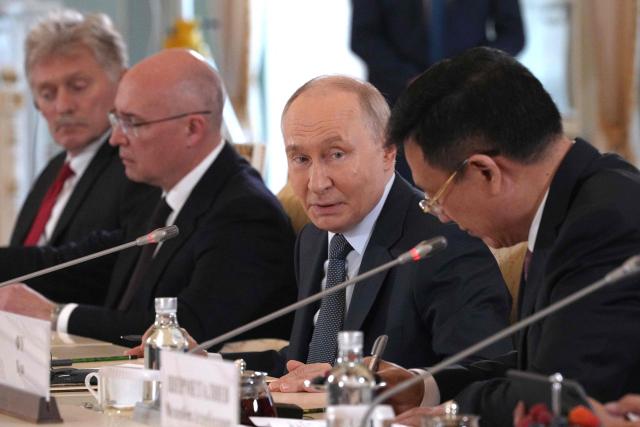 Russian President Vladimir Putin speaks to President of Xinhua News Agency Fu Hua during a meeting with representatives of international news agencies as General Director of the Russian news agency TASS, Andrey Kondrashov and Kremlin spokesman Dmitry Peskov sit near, on the sidelines of the St. Petersburg International Economic Forum at the Constantine Palace in Saint Petersburg on June 4, 2026. (Photo by Dmitry LOVETSKY / POOL / AFP)