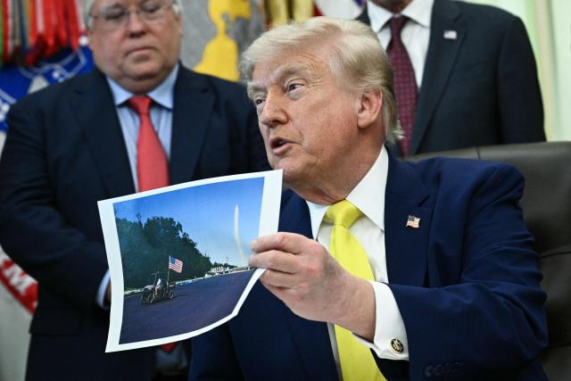 US President Donald Trump holds a picture of the newly resurfaced Reflecting Pool on the National Mall as he speaks in the Oval Office of the White House in Washington, DC on June 4, 2026. (Photo by Brendan SMIALOWSKI / AFP)