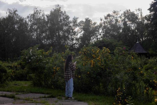 A local resident takes pictures of blooming flowers at the botanical garden in Kyiv on June 4, 2026, amid the Russian invasion of Ukraine. (Photo by Tetiana DZHAFAROVA / AFP)