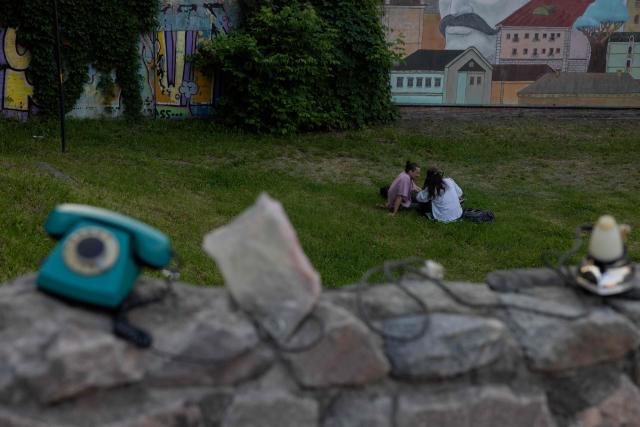 Local residents sit on a grass lawn in Kyiv on June 4, 2026, amid the Russian invasion of Ukraine. (Photo by Tetiana DZHAFAROVA / AFP)