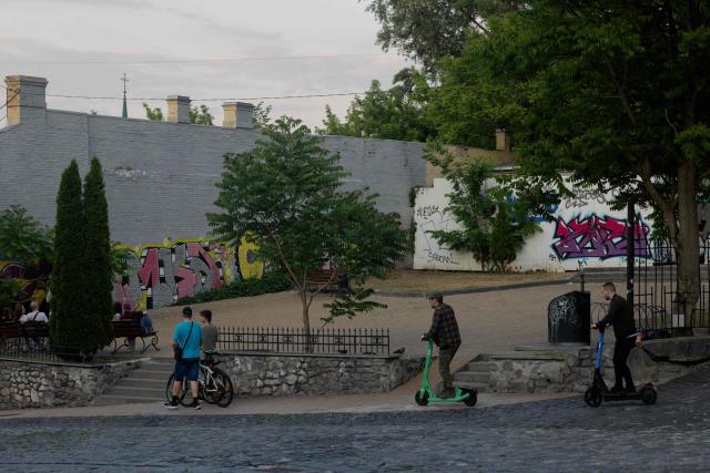 Local residents ride electric scooters down the street in Kyiv on June 4, 2026, amid the Russian invasion of Ukraine. (Photo by Tetiana DZHAFAROVA / AFP)