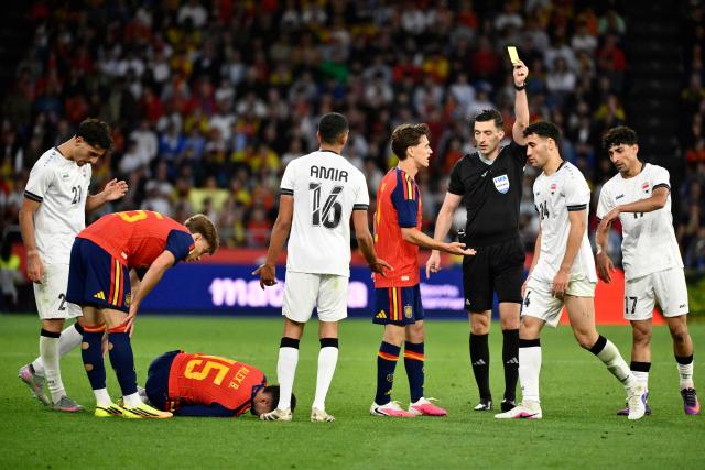 German referee Florian Badstubner presents a yellow card to Iraq's midfielder #24 Zaid Ismael (2R) after fouling Spain's midfielder #15 Alex Baena during the international friendly football match between Spain and Iraq ahead of the 2026 FIFA World Cup football tournament, at the Riazor stadium in A Coruna, northern Spain, on June 4, 2026. (Photo by Ander Gillenea / AFP)
