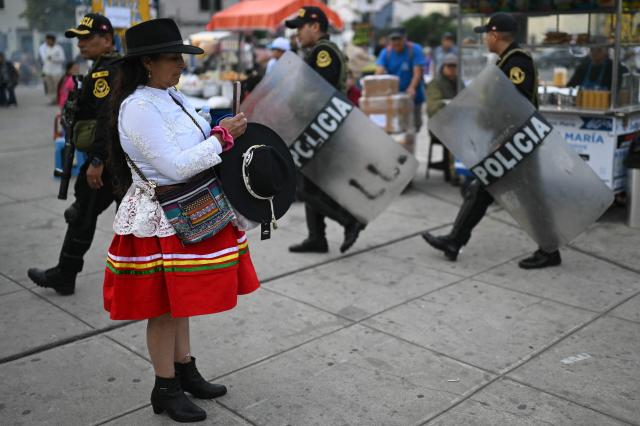 A woman takes a snapshot as Peruvian policeman take position before the start of the closing campaign rally of Peru's presidential candidate for the Juntos por el Peru party, Roberto Sanchez, in Lima on June 4, 2026. Right-wing candidate Keiko Fujimori and leftist Roberto Sanchez will face off in Peru's presidential runoff on June 7, 2026. (Photo by ERNESTO BENAVIDES / AFP)