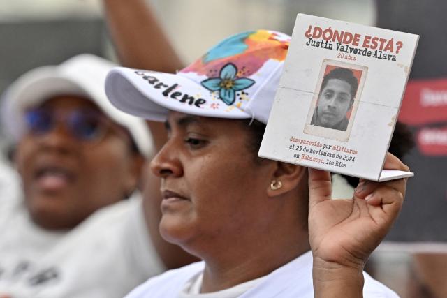 A woman shows a sign with the portrait of a victim as she takes part in a protest during a public apology event on behalf of the Ecuadorian government for the forced disappearance of the four children from the Malvinas, at the Rotonda hemicycle in Guayaquil, Ecuador, on June 4, 2026. (Photo by MARCOS PIN / AFP)