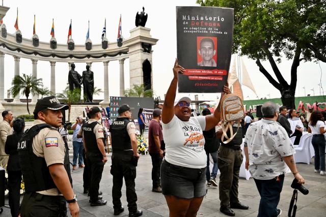A woman shows a sign with the portrait of a victim as she takes part in a protest during a public apology event on behalf of the Ecuadorian government for the forced disappearance of the four children from the Malvinas, at the Rotonda hemicycle in Guayaquil, Ecuador, on June 4, 2026. (Photo by MARCOS PIN / AFP)