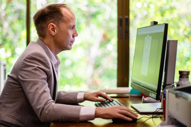 This photo taken on June 2, 2026 shows German lecturer Felix Puelm posing to show him browsing an online database published by Die Zeit, a German national weekly newspaper, as he looks at the National Socialist German Workers’ party (NSDAP) membership card of his grandmother Brigitte, at Silpakorn University, in Nakhon Pathom province, west of Bangkok. (Photo by ANTHONY WALLACE / AFP)