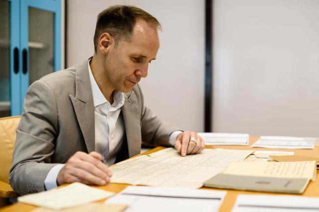 This photo taken on June 2, 2026 shows German lecturer Felix Puelm looking at various historical family documents, including a copy of his grandmother Brigitte’s National Socialist German Workers’ party (NSDAP) membership card, that he found in an online database published by Die Zeit, a German national weekly newspaper, at Silpakorn University, in Nakhon Pathom province, west of Bangkok. (Photo by ANTHONY WALLACE / AFP)