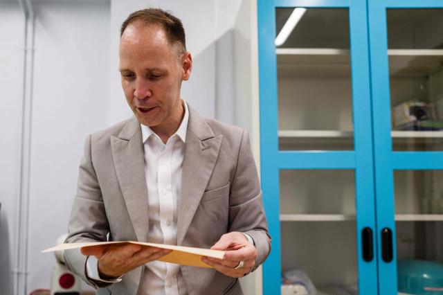This photo taken on June 2, 2026 shows German lecturer Felix Puelm looking at a printed National Socialist German Workers’ party (NSDAP) membership card of his grandmother Brigitte, that he found in an online database published by Die Zeit, a German national weekly newspaper, at Silpakorn University, in Nakhon Pathom province, west of Bangkok. (Photo by ANTHONY WALLACE / AFP)