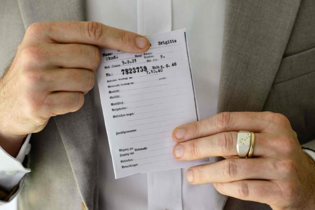 This photo taken on June 2, 2026 shows German lecturer Felix Puelm holding a printed copy of the National Socialist German Workers’ party (NSDAP) membership card of his grandmother Brigitte, which he found on an online database published by Die Zeit, a German national weekly newspaper, at Silpakorn University, in Nakhon Pathom province, west of Bangkok. (Photo by ANTHONY WALLACE / AFP)