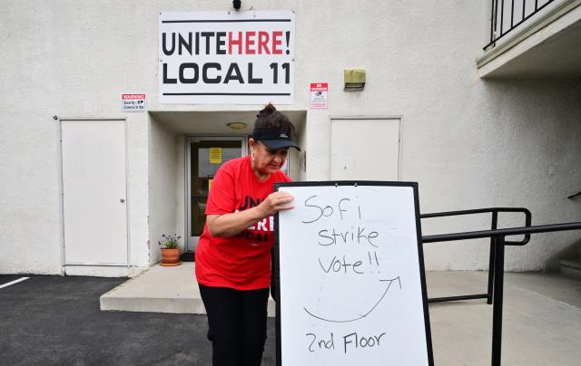 Yolanda Fierro, a suites runner at SoFi Stadium, moves a sign into position at union headquarters where stadium workers will vote on whether to authorize a strike amid a contract dispute, days before the 2026 FIFA World Cup begins in Inglewood, California, on June 4, 2026. Hundreds of workers at Los Angeles SoFi Stadium began voting on June 4 on a proposal to go on strike during the World Cup, which kicks off in a week, after negotiations over their safety and wage demands reached an impasse. The vote was taking place at the offices of the Unite Here Local 11 union in Inglewood (south of Los Angeles) and will continue until Friday night. (Photo by Frederic J. BROWN / AFP)