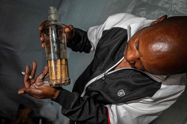 Dauda Tshimanga holds a bottle of traditional medicine in his laboratory in Bunia, in the eastern Democratic Republic of the Congo, on June 2, 2026. Although there is still no vaccine or official treatment for the Bundibugyo virus, the prevalent strain in the current Ebola outbreak in the DRC, Dauda Tshimanga and his wife Mariam Kabika, a couple of traditional healers, are "certain" they have a found a remedy to treat it. “I am going to mix these leaves with other ingredients (...) and boil them,” explains Mariam, who practices in the city of Bunia, the capital of Ituri and the epicentre of the epidemic. "Once the mixture is ready, I’ll be able to give it to someone who has Ebola." (Photo by Glody MURHABAZI / AFP)